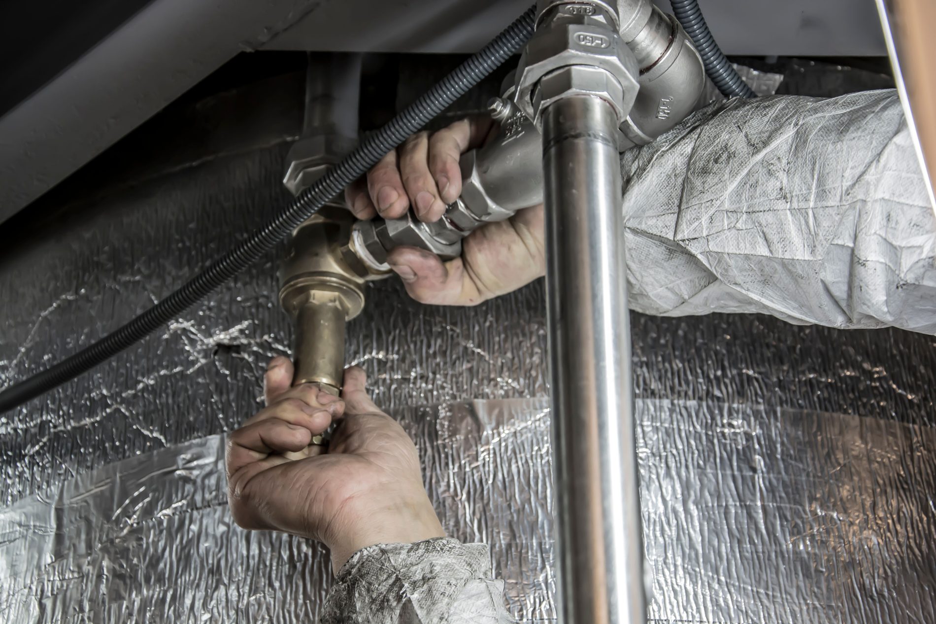 Plumber repairing pipework under a sink